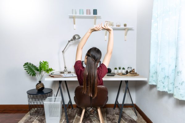 Office worker stretching beside a desk during the workday.