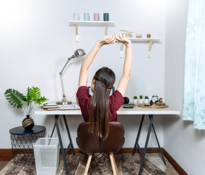 Office worker stretching beside a desk during the workday.
