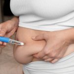Pharmacist holding a prescription weight-loss injection in a pharmacy.