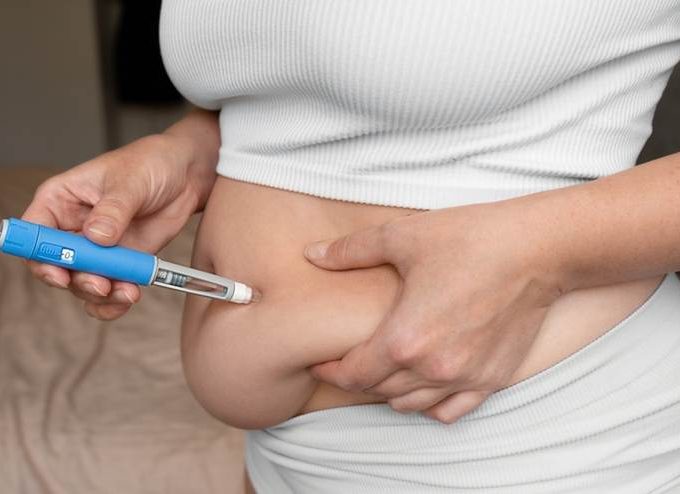 Pharmacist holding a prescription weight-loss injection in a pharmacy.