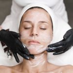 Woman examining her jawline and skin in a mirror before considering an aesthetic treatment