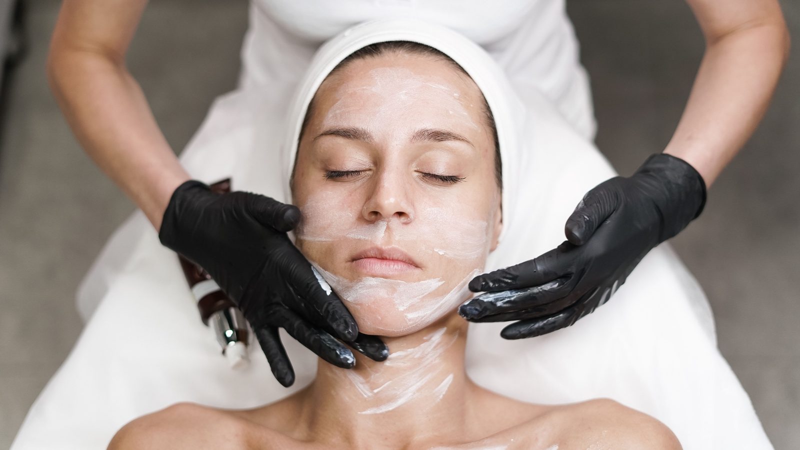 Woman examining her jawline and skin in a mirror before considering an aesthetic treatment