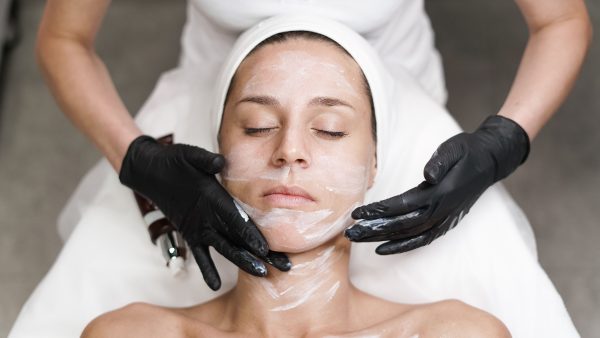 Woman examining her jawline and skin in a mirror before considering an aesthetic treatment