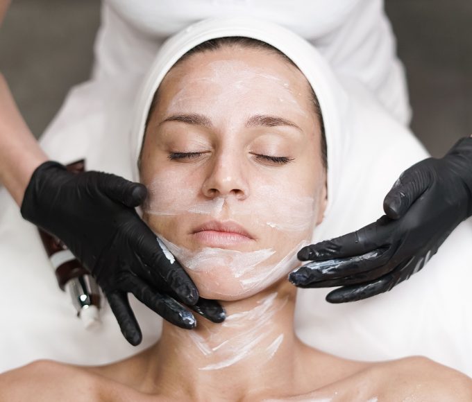 Woman examining her jawline and skin in a mirror before considering an aesthetic treatment
